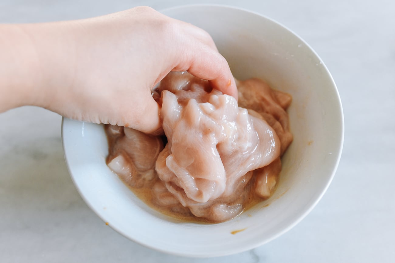 Massaging marinade ingredients into sliced chicken