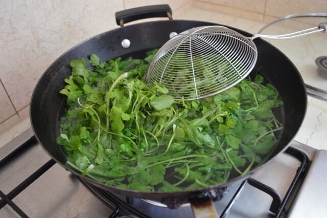 Blanching fresh shepherd's purse in a wok