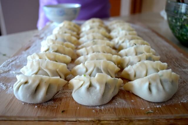 pleated dumplings lined up on cutting board
