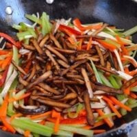 Stir-frying spiced tofu with celery, carrots, and peppers in wok