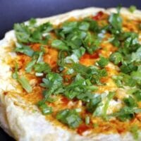 Frying pancake with egg and spicy bean sauce, cilantro, and scallion