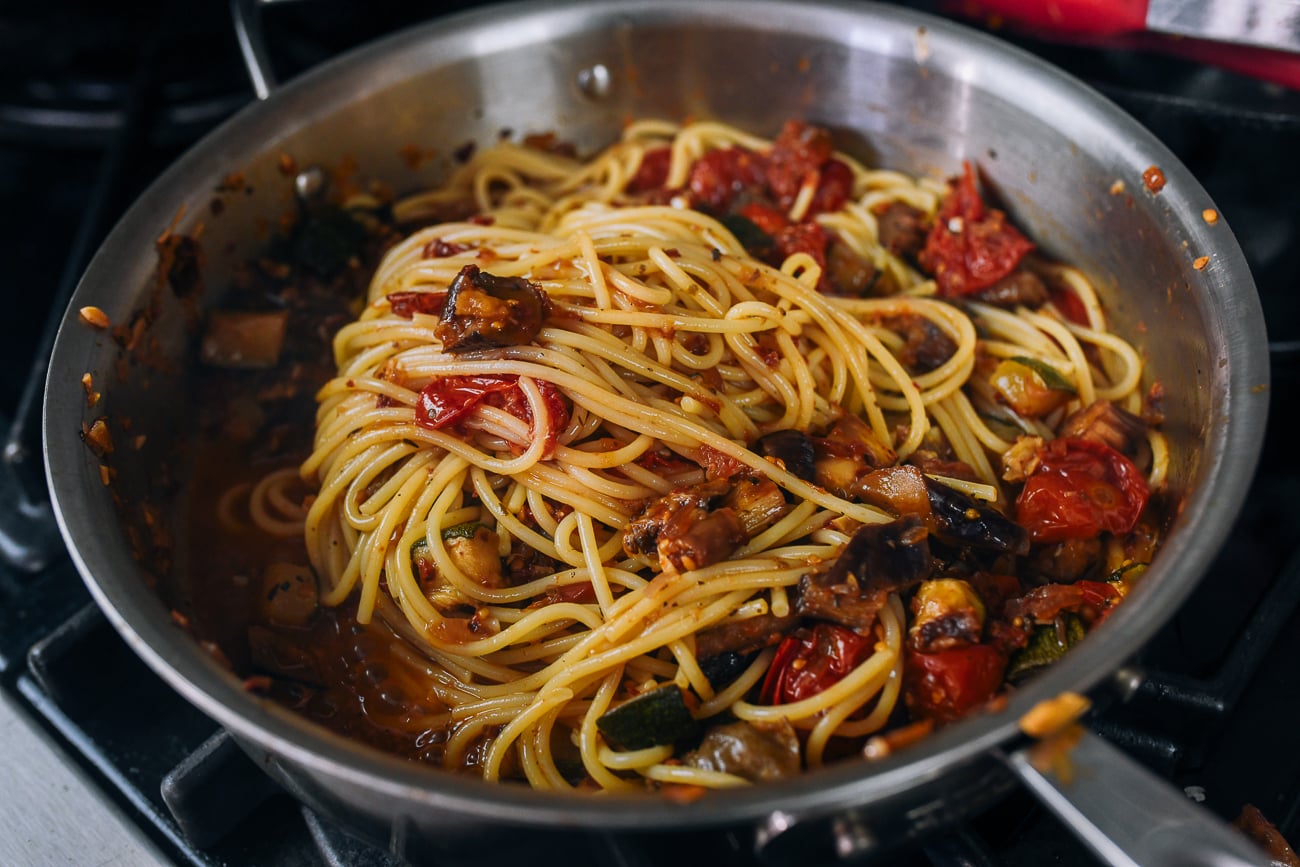 mixing spaghetti with ratatouille in pan