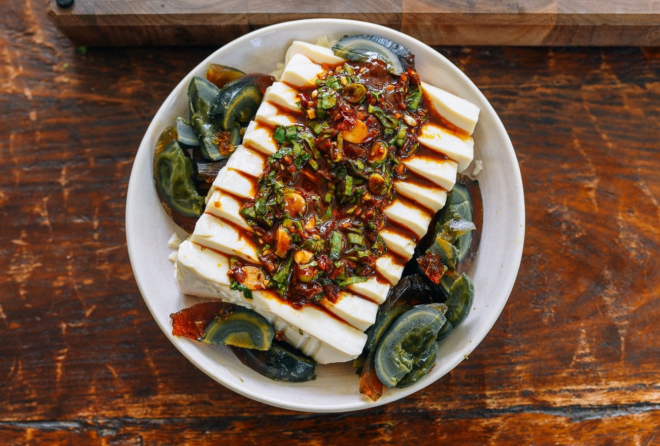 silken tofu surrounded by thousand year old egg, with spicy sauce on top