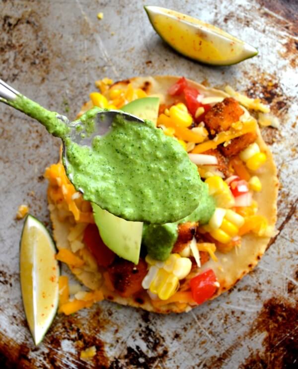 Spooning green sauce over tofu tacos by thewoksoflife.com