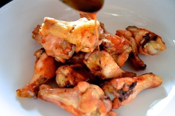 Pouring sauce onto roasted wings