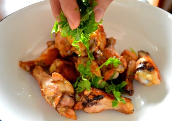 Sprinkling chopped cilantro over sauced wings