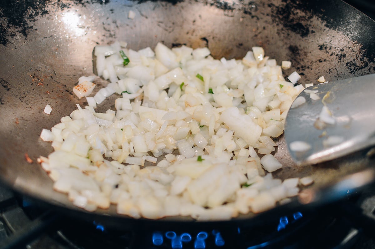 Stir-frying chopped onions in wok, thewoksoflife.com