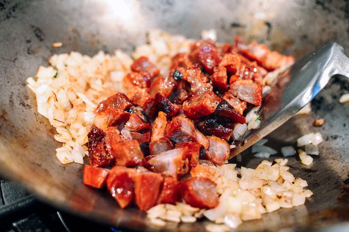 adding cubed roast pork to onion in wok