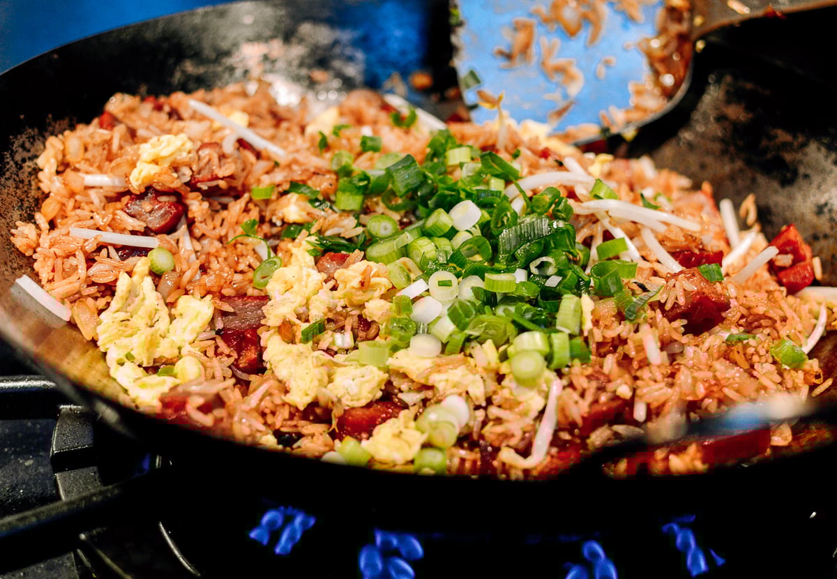 Adding scallions to fried rice, by thewoksoflife.com