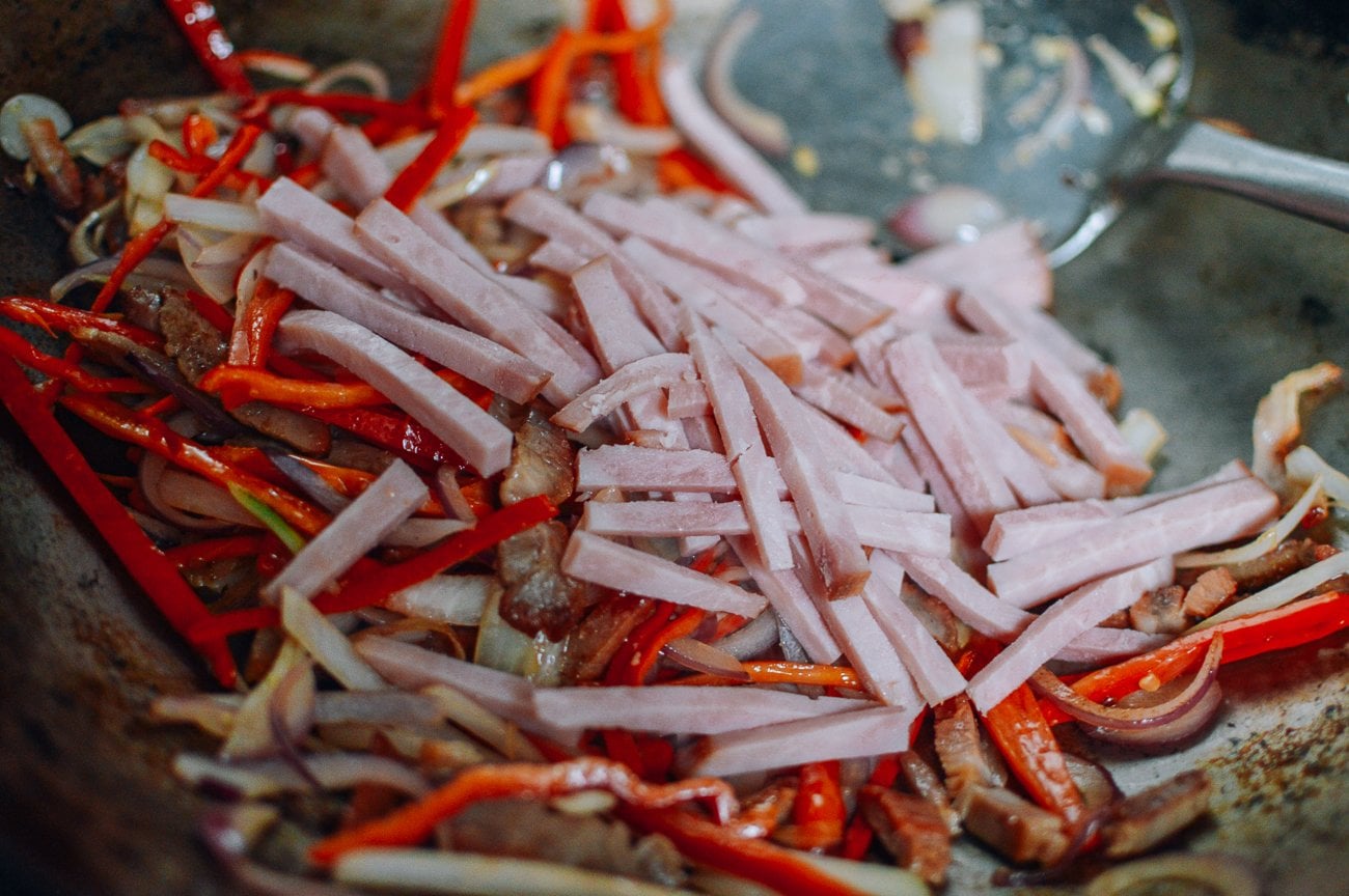 adding ham to wok with vegetables and char siu