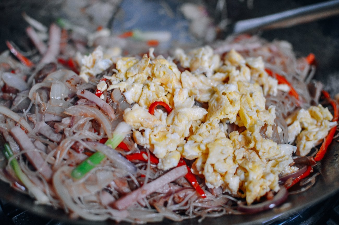 adding egg to noodles and vegetables