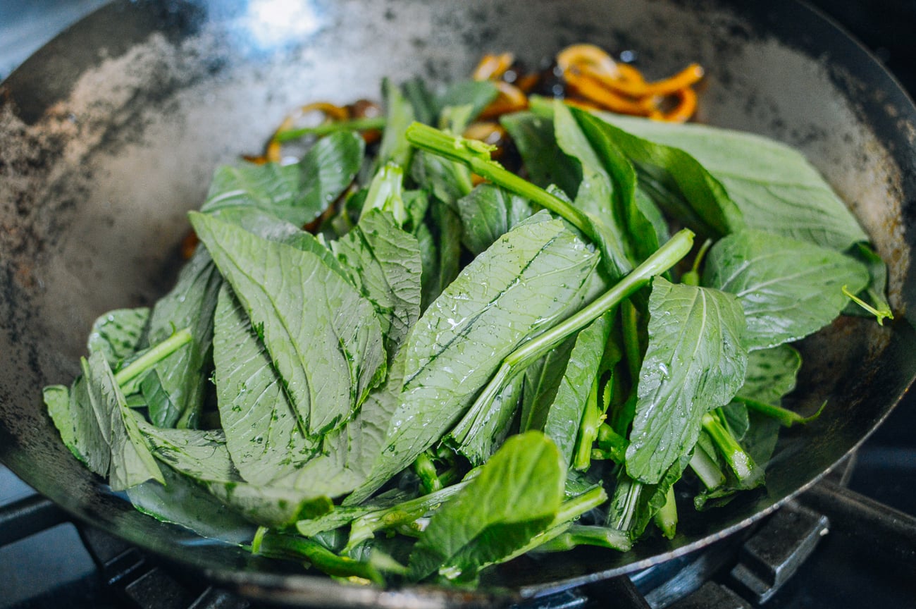 leafy greens in wok with noodles