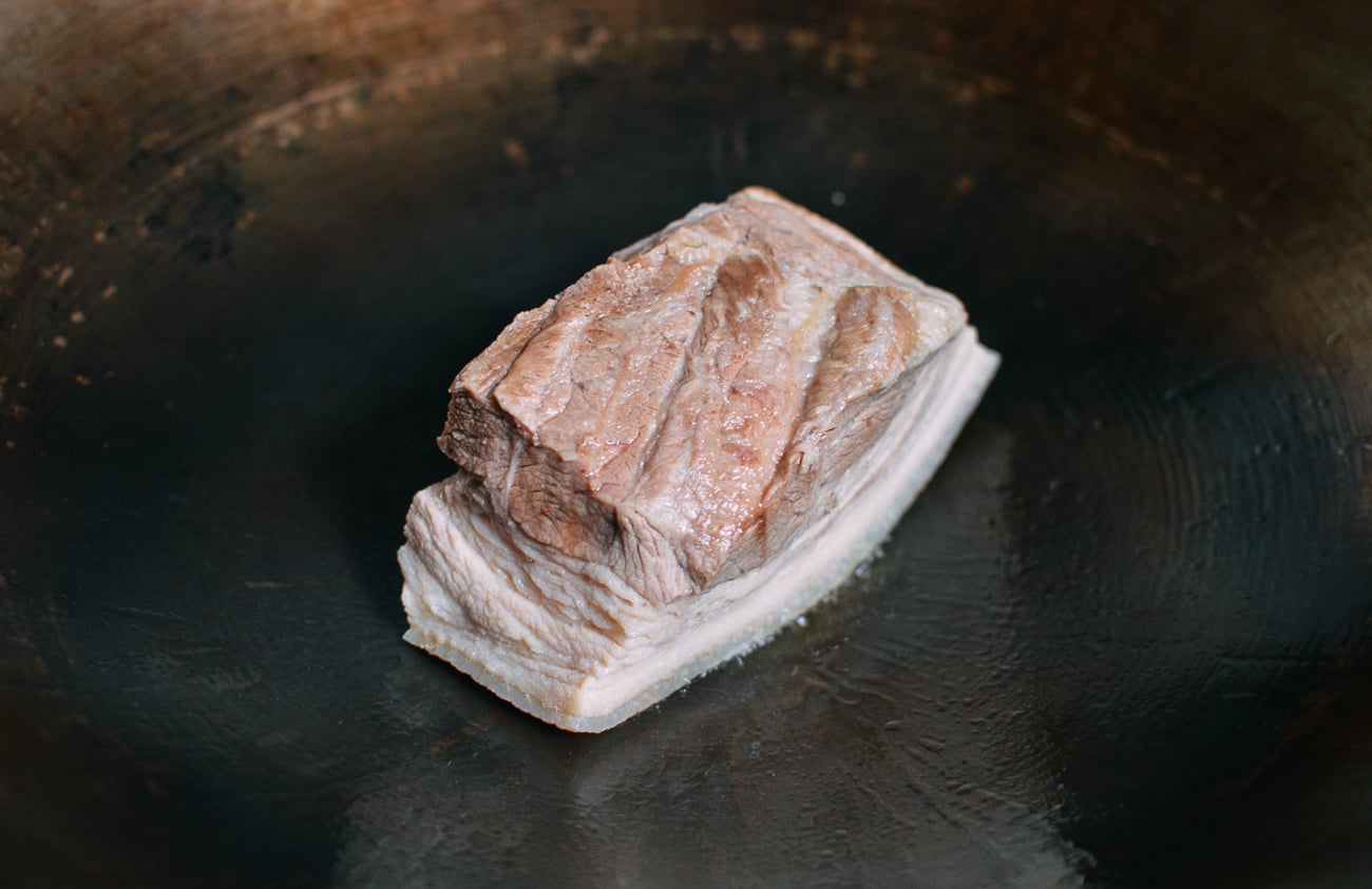 searing chunk of pork belly in wok