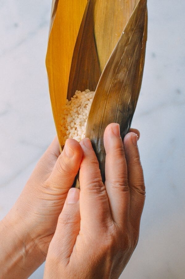 Before you start, there are a few things to remember: You must cut away at least half an inch off the bottom of every leaf you use. Make sure the kitchen twine won’t break easily. To do this, it’s best to wet the twine first by soaking it in a bowl of water. It’s best to tie one end of the twine to an anchor point or kitchen fixture (e.g. you kitchen sink), because you will only have one hand to tie the zongzi. Your other hand will be holding the zongzi. Or have someone help you out! Making zongzi is like making a big batch of dumplings or wontons—all hands on deck! Just make sure that the newbies are holding the strings and the seasoned pros are doing the folding! Hah! If leaves rip anywhere during the wrapping process, you’ll need to start over and discard the ripped leaf. That’s why I call for more leaves than is technically needed. Some of the leaves are bound to get ripped.