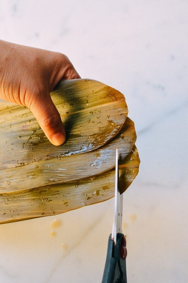 Before you start, there are a few things to remember: You must cut away at least half an inch off the bottom of every leaf you use. Make sure the kitchen twine won’t break easily. To do this, it’s best to wet the twine first by soaking it in a bowl of water. It’s best to tie one end of the twine to an anchor point or kitchen fixture (e.g. you kitchen sink), because you will only have one hand to tie the zongzi. Your other hand will be holding the zongzi. Or have someone help you out! Making zongzi is like making a big batch of dumplings or wontons—all hands on deck! Just make sure that the newbies are holding the strings and the seasoned pros are doing the folding! Hah! If leaves rip anywhere during the wrapping process, you’ll need to start over and discard the ripped leaf. That’s why I call for more leaves than is technically needed. Some of the leaves are bound to get ripped.