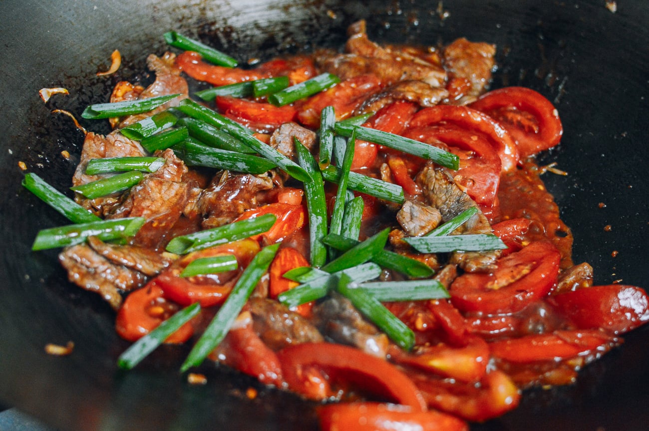 stir-frying Cantonese beef and tomato with scallions