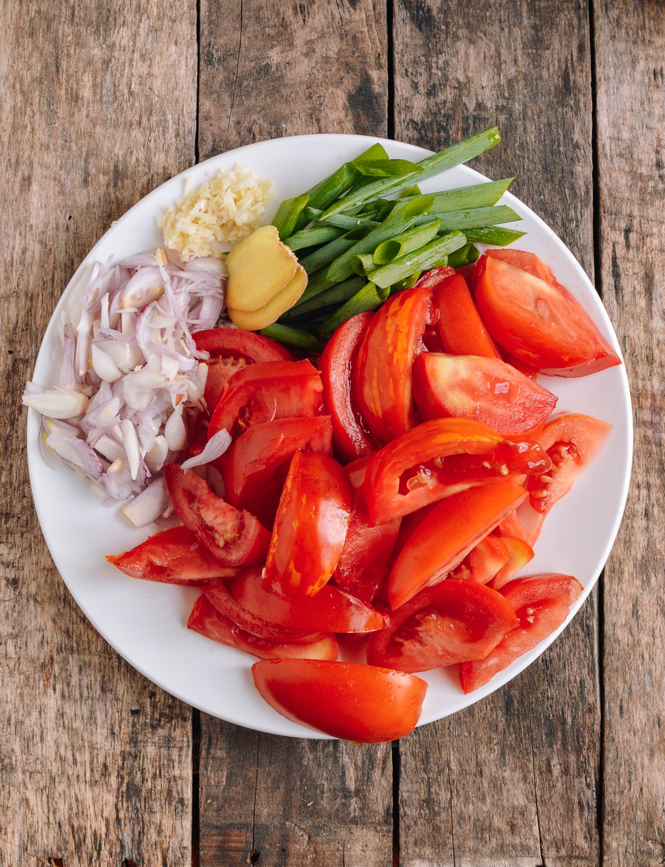 plate with tomato wedges, shallot, ginger, garlic, and scallion