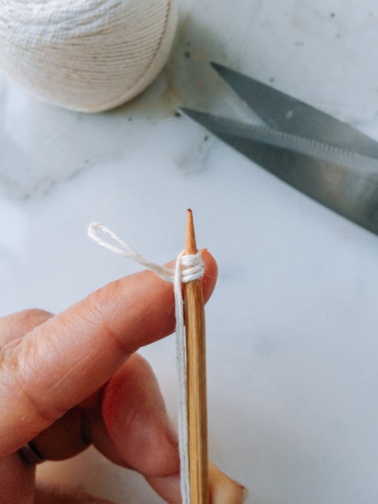 Tying kitchen string around the tip of a bamboo skewer