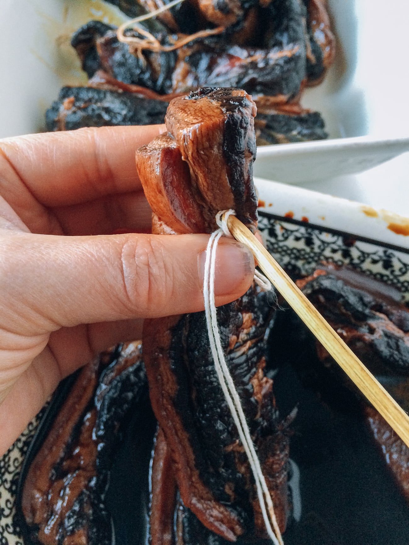 Using a bamboo skewer to run kitchen string through pork belly