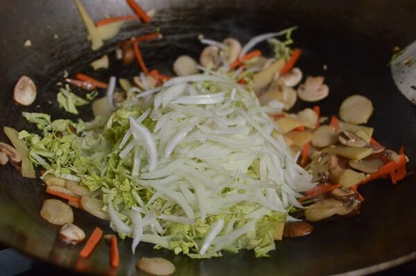 Take the shrimp and noodles out of the refrigerator, and let them come up to room temperature. One trick for the noodles is to soak the whole bag (unopened) in hot water, which speeds up the warming process without making the noodles soggy. If you can’t find lo mein noodles, you can actually substitute dried linguini. Just cook until al dente, drain, and immediately toss with 1 tablespoon of vegetable oil, working the oil into the pasta so the noodles don't stick together. Always prepare your noodles just before you are ready to make the dish, so they don’t dry out and remain at room temperature or warmer. This makes the stir-frying process much easier. Combine the sugar, soy sauces, oyster sauce, sesame oil, and white pepper in a bowl until the sugar is dissolved and set aside. Heat a large wok over high heat until it just starts to smoke, and add 1 tablespoon of oil around the perimeter of the wok. Quickly spread the shrimp around your wok and let them sear for 10-15 seconds on each side. Immediately transfer the shrimp to a plate and set aside. Return the wok to the highest heat possible and add 2 tablespoons oil, along with the garlic. After a few seconds, add the mushrooms, carrots, bamboo shoots, and water chestnuts and stir-fry for 30 seconds. Next, spread the Shaoxing wine around the perimeter of the wok, and then add the napa cabbage. Stir-fry for another 30 seconds. Spread the noodles evenly over the vegetables and give everything a good stir for 1 minute. Now, you can see why you want everything at room temperature, or everything will be overcooked and mushy by the time it heats up! At this point, the noodles should be softened, so add in the sauce mixture you set aside earlier and mix until everything is well combined. Stir-fry for another 30 seconds using a scooping motion, until the sauce is well distributed. Add in the shrimp, snow peas, bean sprouts, and scallions. Mix well for another 2 minutes and serve!