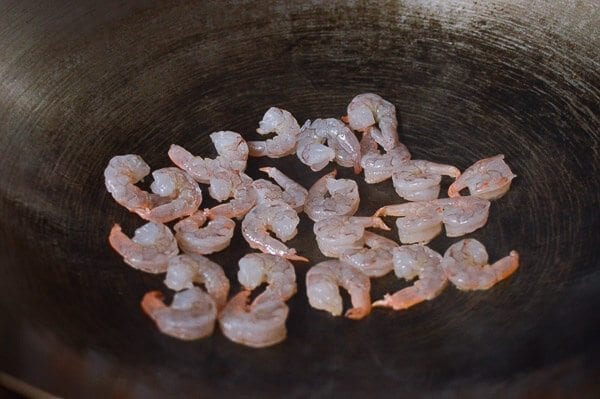 Take the shrimp and noodles out of the refrigerator, and let them come up to room temperature. One trick for the noodles is to soak the whole bag (unopened) in hot water, which speeds up the warming process without making the noodles soggy. If you can’t find lo mein noodles, you can actually substitute dried linguini. Just cook until al dente, drain, and immediately toss with 1 tablespoon of vegetable oil, working the oil into the pasta so the noodles don't stick together. Always prepare your noodles just before you are ready to make the dish, so they don’t dry out and remain at room temperature or warmer. This makes the stir-frying process much easier. Combine the sugar, soy sauces, oyster sauce, sesame oil, and white pepper in a bowl until the sugar is dissolved and set aside. Heat a large wok over high heat until it just starts to smoke, and add 1 tablespoon of oil around the perimeter of the wok. Quickly spread the shrimp around your wok and let them sear for 10-15 seconds on each side. Immediately transfer the shrimp to a plate and set aside. Return the wok to the highest heat possible and add 2 tablespoons oil, along with the garlic. After a few seconds, add the mushrooms, carrots, bamboo shoots, and water chestnuts and stir-fry for 30 seconds. Next, spread the Shaoxing wine around the perimeter of the wok, and then add the napa cabbage. Stir-fry for another 30 seconds. Spread the noodles evenly over the vegetables and give everything a good stir for 1 minute. Now, you can see why you want everything at room temperature, or everything will be overcooked and mushy by the time it heats up! At this point, the noodles should be softened, so add in the sauce mixture you set aside earlier and mix until everything is well combined. Stir-fry for another 30 seconds using a scooping motion, until the sauce is well distributed. Add in the shrimp, snow peas, bean sprouts, and scallions. Mix well for another 2 minutes and serve!
