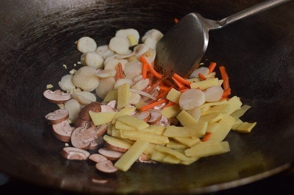Take the shrimp and noodles out of the refrigerator, and let them come up to room temperature. One trick for the noodles is to soak the whole bag (unopened) in hot water, which speeds up the warming process without making the noodles soggy. If you can’t find lo mein noodles, you can actually substitute dried linguini. Just cook until al dente, drain, and immediately toss with 1 tablespoon of vegetable oil, working the oil into the pasta so the noodles don't stick together. Always prepare your noodles just before you are ready to make the dish, so they don’t dry out and remain at room temperature or warmer. This makes the stir-frying process much easier. Combine the sugar, soy sauces, oyster sauce, sesame oil, and white pepper in a bowl until the sugar is dissolved and set aside. Heat a large wok over high heat until it just starts to smoke, and add 1 tablespoon of oil around the perimeter of the wok. Quickly spread the shrimp around your wok and let them sear for 10-15 seconds on each side. Immediately transfer the shrimp to a plate and set aside. Return the wok to the highest heat possible and add 2 tablespoons oil, along with the garlic. After a few seconds, add the mushrooms, carrots, bamboo shoots, and water chestnuts and stir-fry for 30 seconds. Next, spread the Shaoxing wine around the perimeter of the wok, and then add the napa cabbage. Stir-fry for another 30 seconds. Spread the noodles evenly over the vegetables and give everything a good stir for 1 minute. Now, you can see why you want everything at room temperature, or everything will be overcooked and mushy by the time it heats up! At this point, the noodles should be softened, so add in the sauce mixture you set aside earlier and mix until everything is well combined. Stir-fry for another 30 seconds using a scooping motion, until the sauce is well distributed. Add in the shrimp, snow peas, bean sprouts, and scallions. Mix well for another 2 minutes and serve!