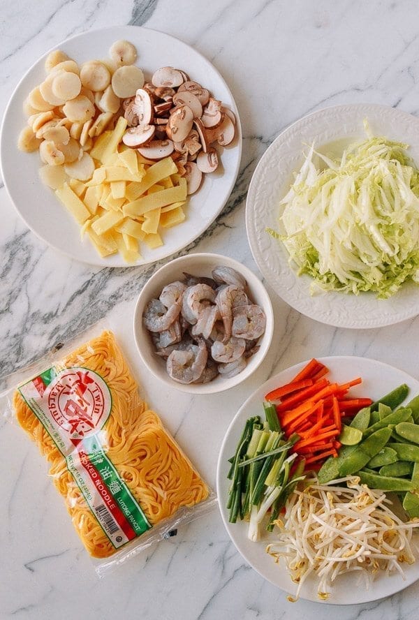 Take the shrimp and noodles out of the refrigerator, and let them come up to room temperature. One trick for the noodles is to soak the whole bag (unopened) in hot water, which speeds up the warming process without making the noodles soggy. If you can’t find lo mein noodles, you can actually substitute dried linguini. Just cook until al dente, drain, and immediately toss with 1 tablespoon of vegetable oil, working the oil into the pasta so the noodles don't stick together. Always prepare your noodles just before you are ready to make the dish, so they don’t dry out and remain at room temperature or warmer. This makes the stir-frying process much easier. Combine the sugar, soy sauces, oyster sauce, sesame oil, and white pepper in a bowl until the sugar is dissolved and set aside. Heat a large wok over high heat until it just starts to smoke, and add 1 tablespoon of oil around the perimeter of the wok. Quickly spread the shrimp around your wok and let them sear for 10-15 seconds on each side. Immediately transfer the shrimp to a plate and set aside. Return the wok to the highest heat possible and add 2 tablespoons oil, along with the garlic. After a few seconds, add the mushrooms, carrots, bamboo shoots, and water chestnuts and stir-fry for 30 seconds. Next, spread the Shaoxing wine around the perimeter of the wok, and then add the napa cabbage. Stir-fry for another 30 seconds. Spread the noodles evenly over the vegetables and give everything a good stir for 1 minute. Now, you can see why you want everything at room temperature, or everything will be overcooked and mushy by the time it heats up! At this point, the noodles should be softened, so add in the sauce mixture you set aside earlier and mix until everything is well combined. Stir-fry for another 30 seconds using a scooping motion, until the sauce is well distributed. Add in the shrimp, snow peas, bean sprouts, and scallions. Mix well for another 2 minutes and serve!