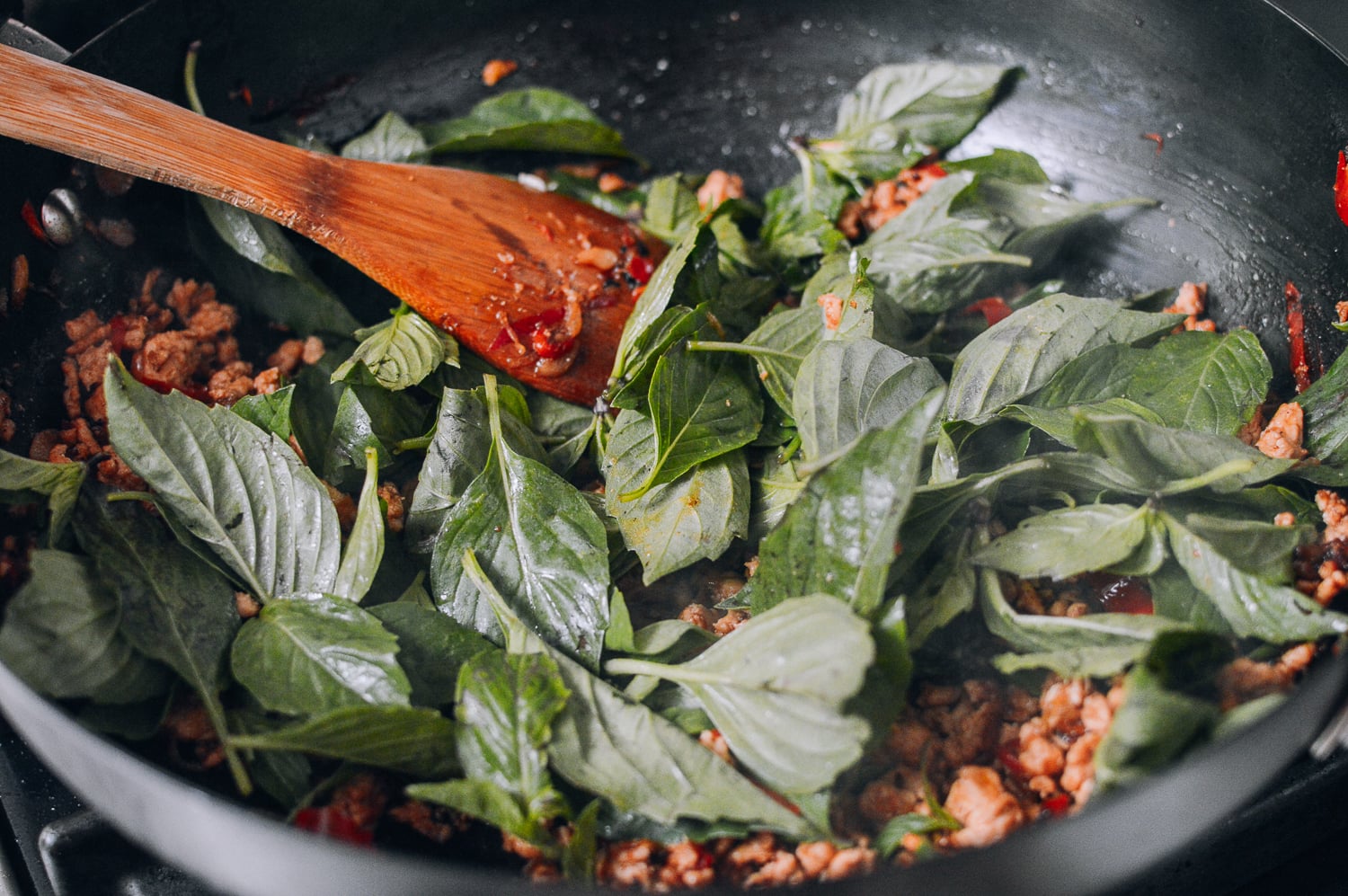 thai basil added to pan of ground chicken
