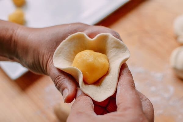 wrapping filling in dough for Cantonese Steamed Custard Buns (Nai Wong Bao), by thewoksoflife.com