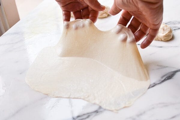 lifting thin oiled dough, by thewoksoflife.com