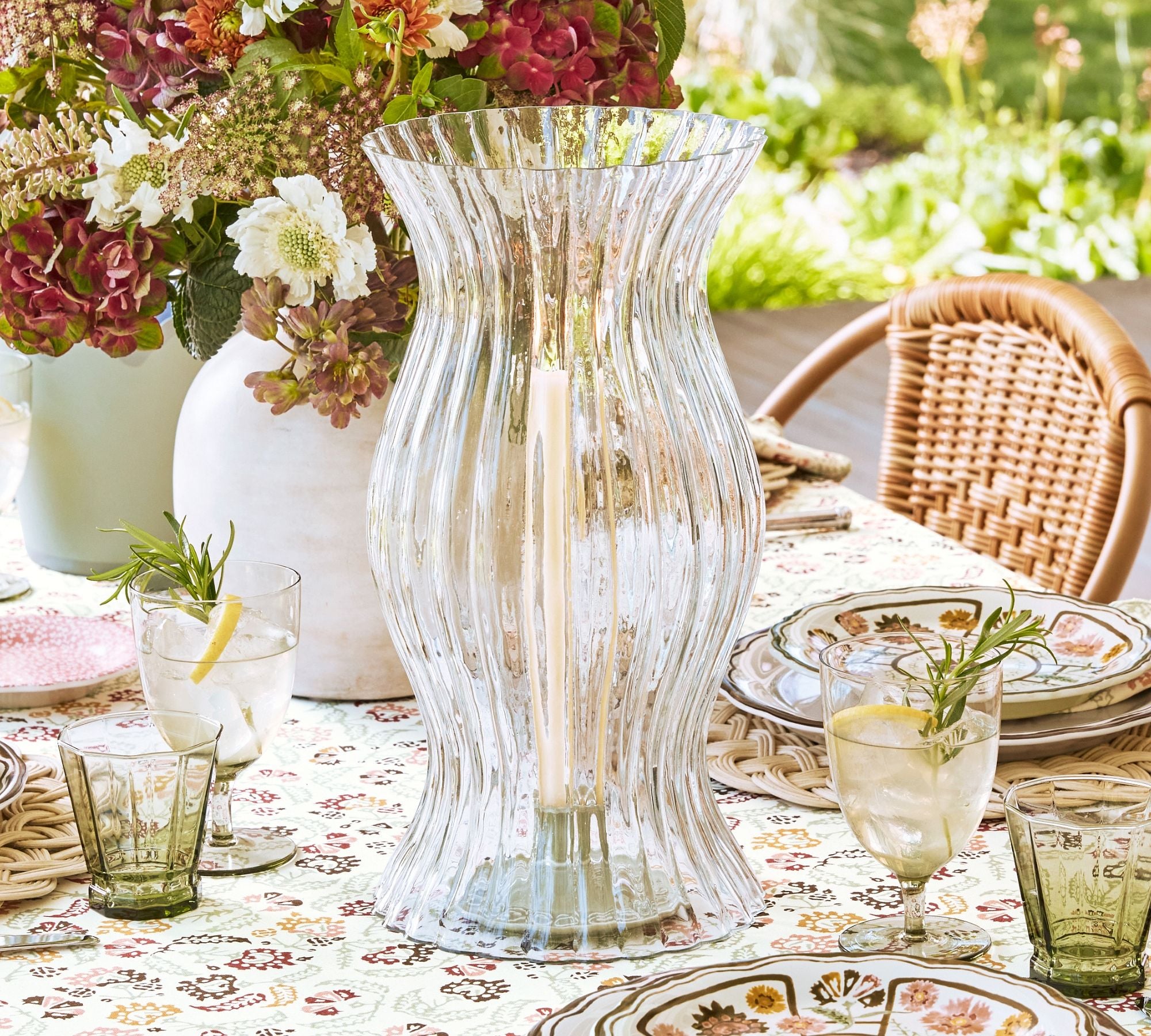 clear crystal hurricane candle holder with a white taper candle and green votive inside 