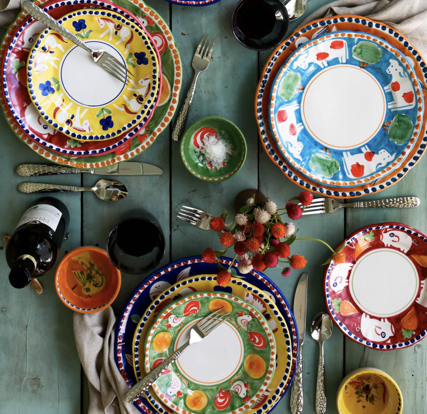 colorful Vietri Campagna place settings on a green wood table 