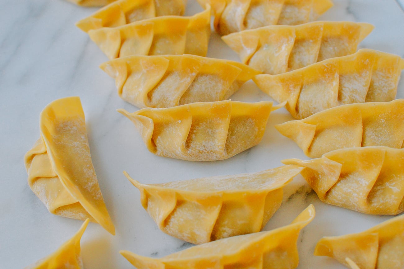 assembled gyoza on parchment paper before cooking