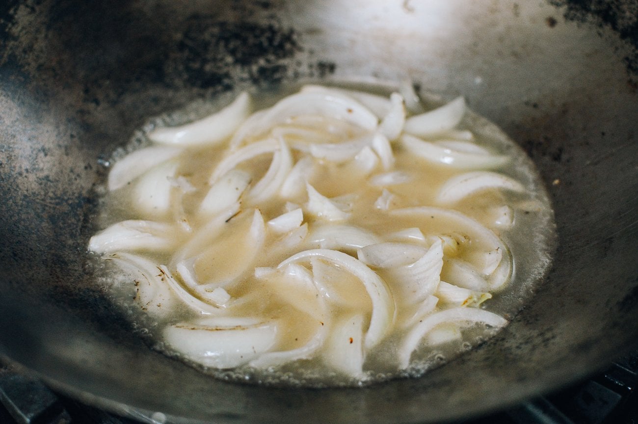 onions and stock in wok