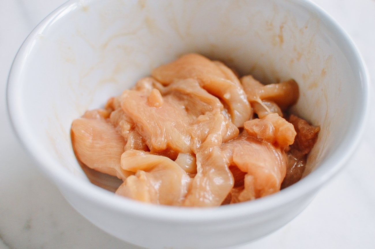 marinating sliced chicken breast in white bowl