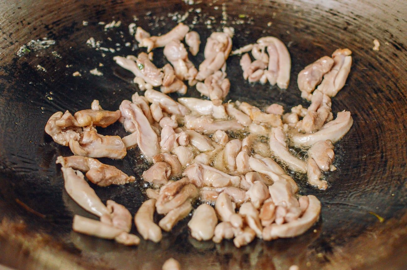 stir-frying strips of chicken in a wok