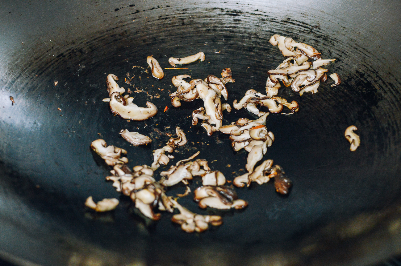 stir-frying sliced mushrooms in wok
