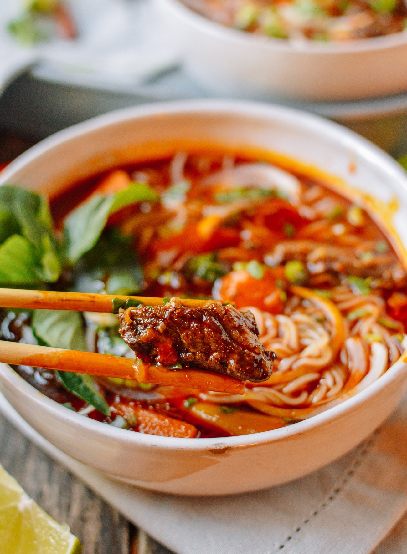 chopsticks picking up beef chunk from bowl of bho kho