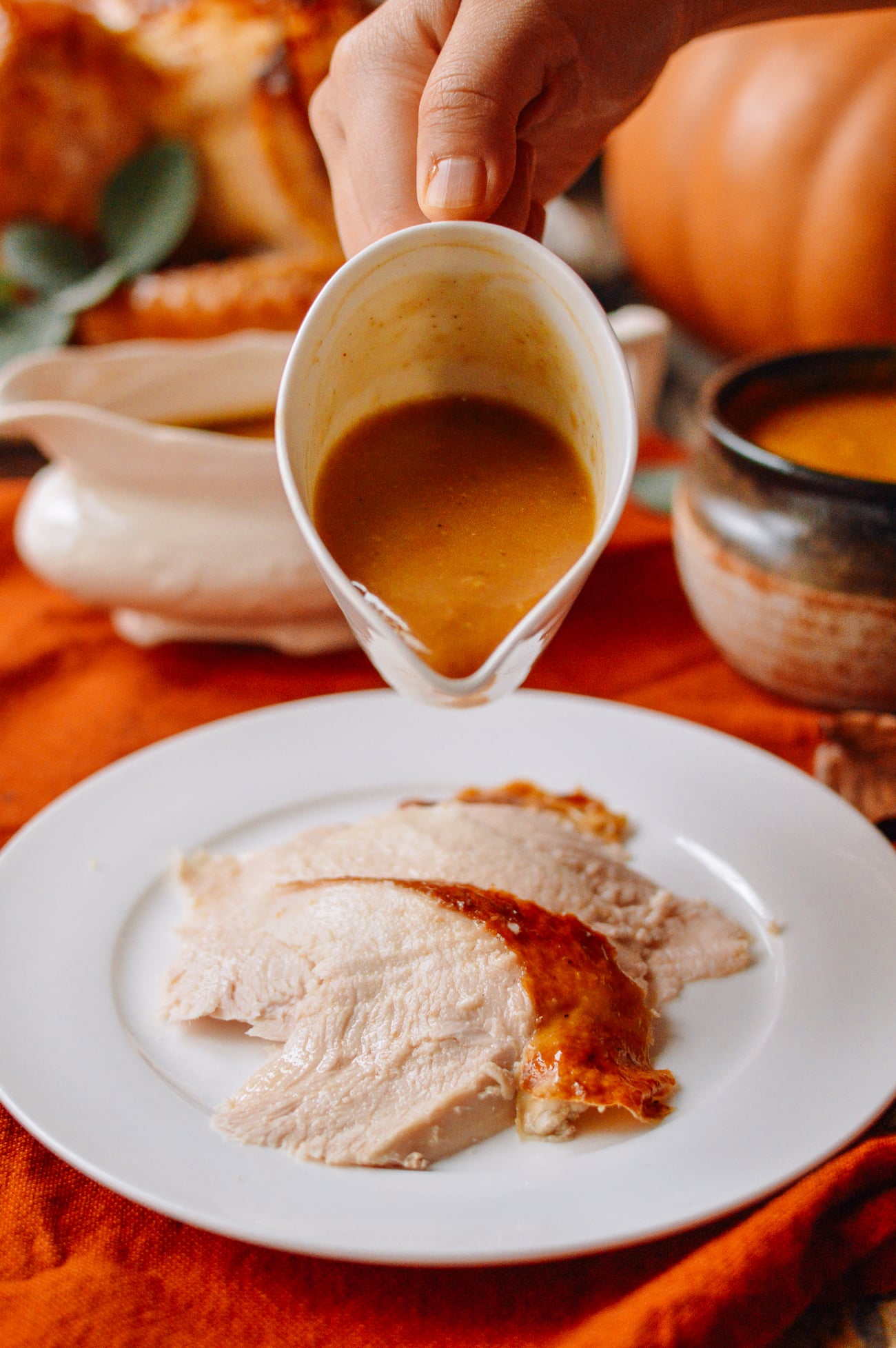 pouring gravy onto sliced roast turkey breast