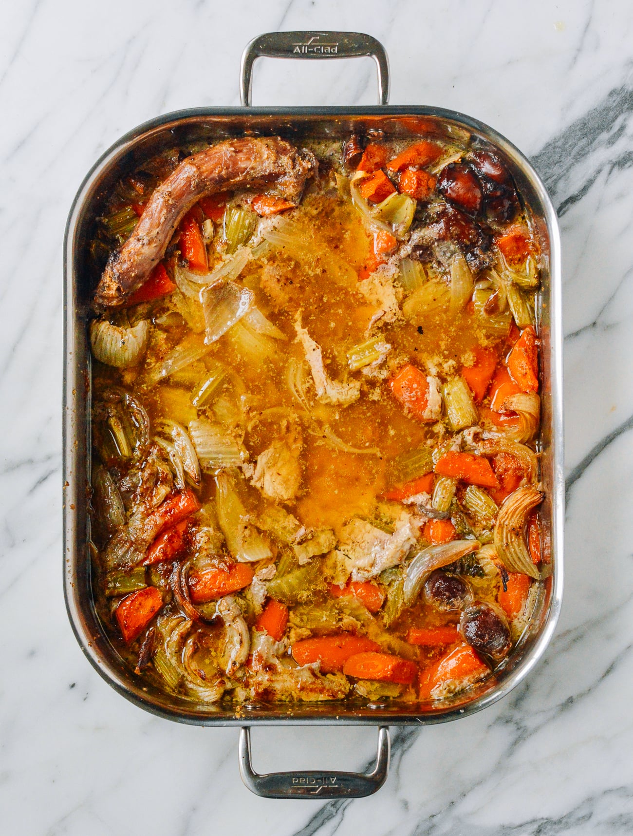vegetables, juices, and turkey neck in roasting pan after roasting turkey