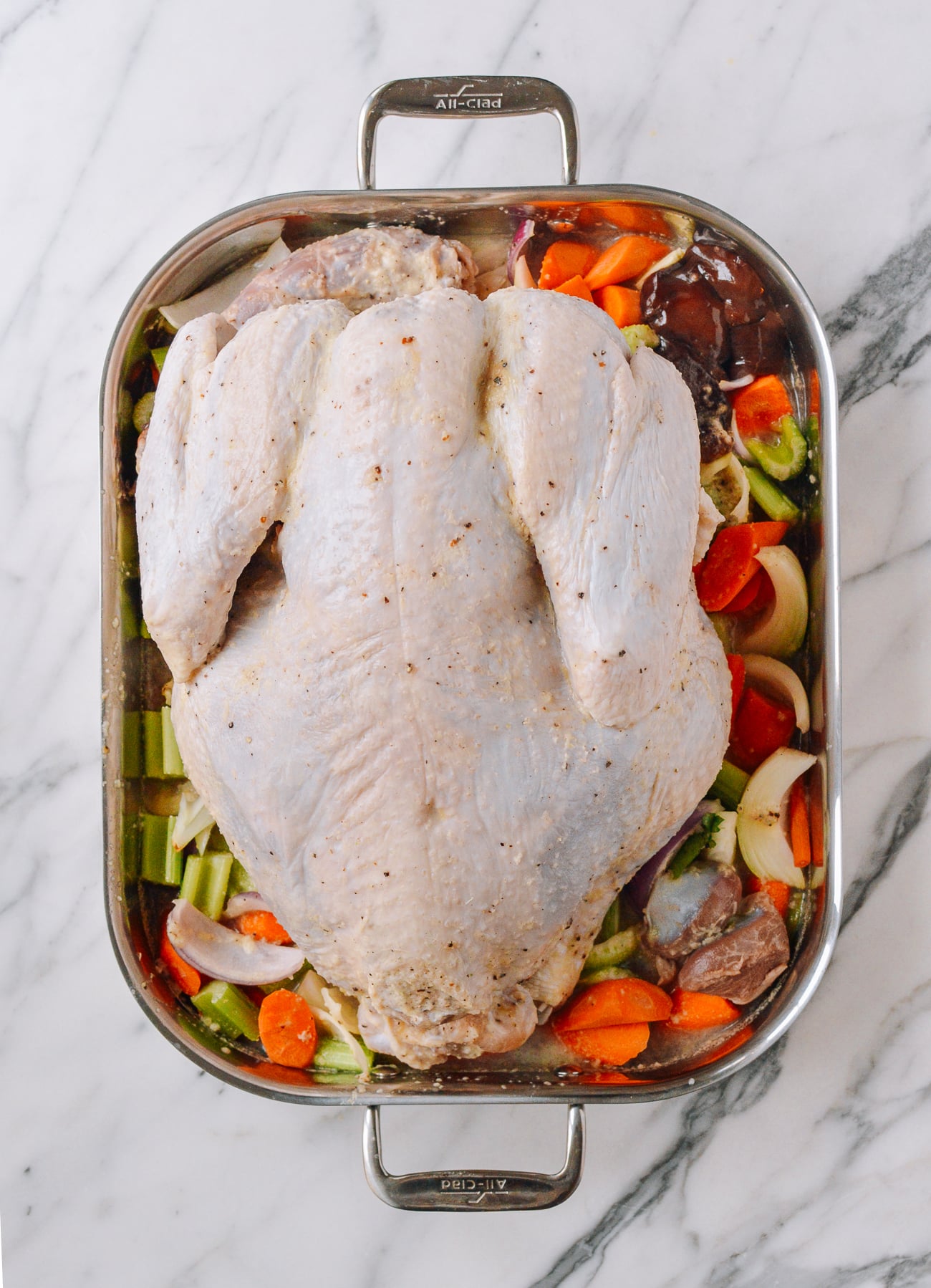 turkey on bed of vegetables in roasting pan before cooking