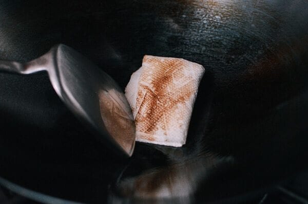 wiping wok with paper towel