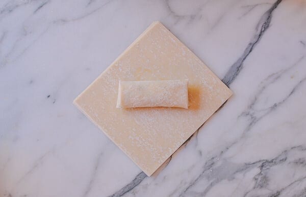 folded egg roll on top of stack of egg roll wrappers