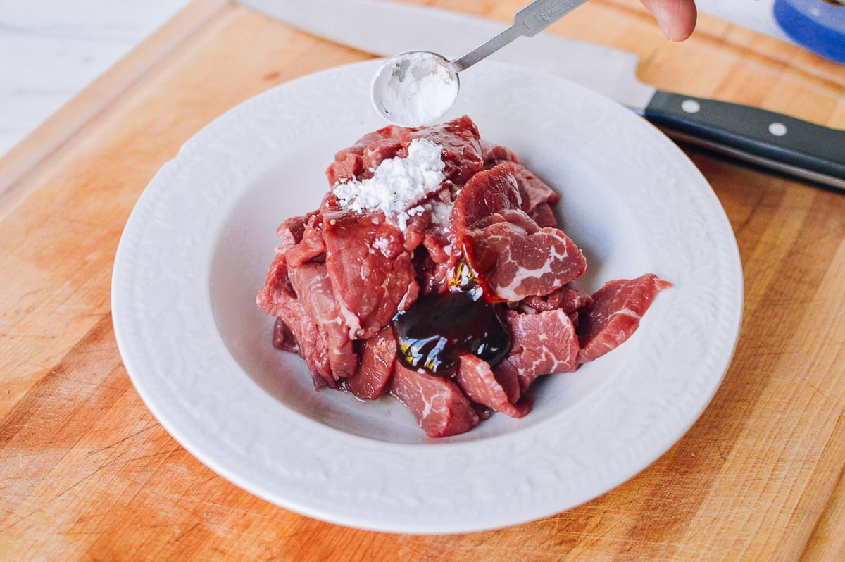 adding corn starch and baking soda marinade to beef by thewoksoflife.com