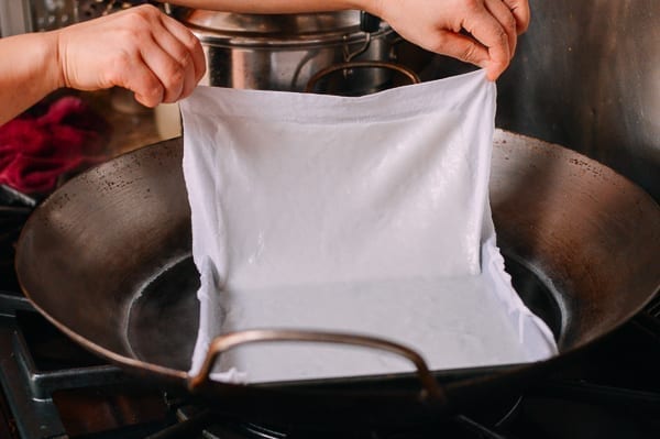 Lifting rice noodle on cloth out of pan, thewoksoflife.com