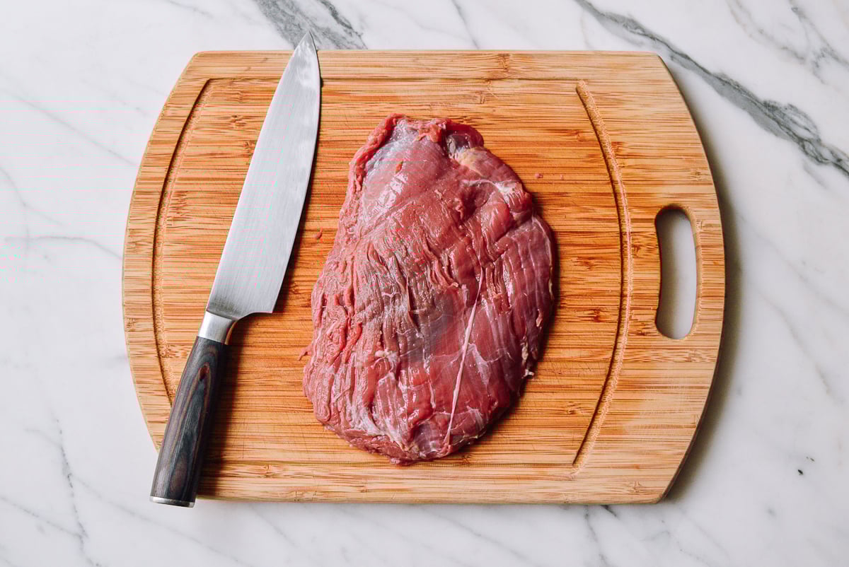 beef flank steak on a cutting board by thewoksoflife.com