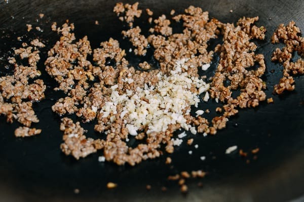 Adding garlic to pork, thewoksoflife.com