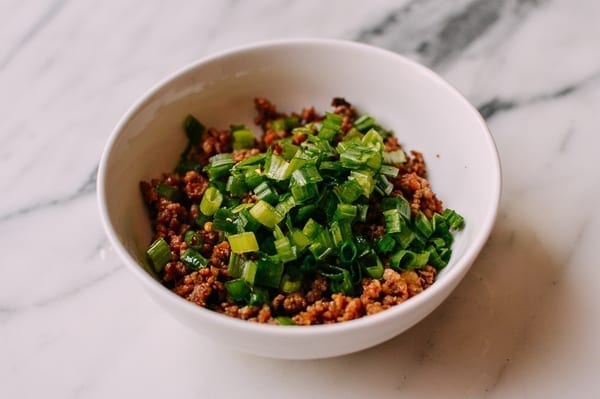 Mixing scallions with ground pork, thewoksoflife.com