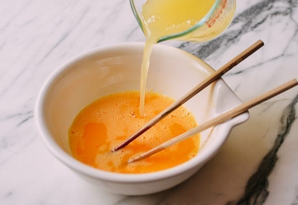 Adding chicken stock to beaten eggs, thewoksoflife.com