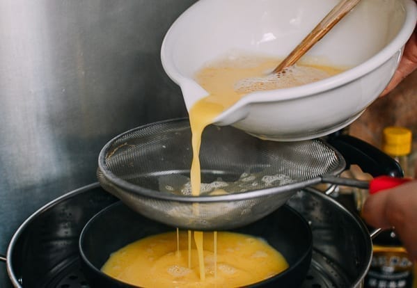 Pouring egg mixture through fine mesh strainer, thewoksoflife.com